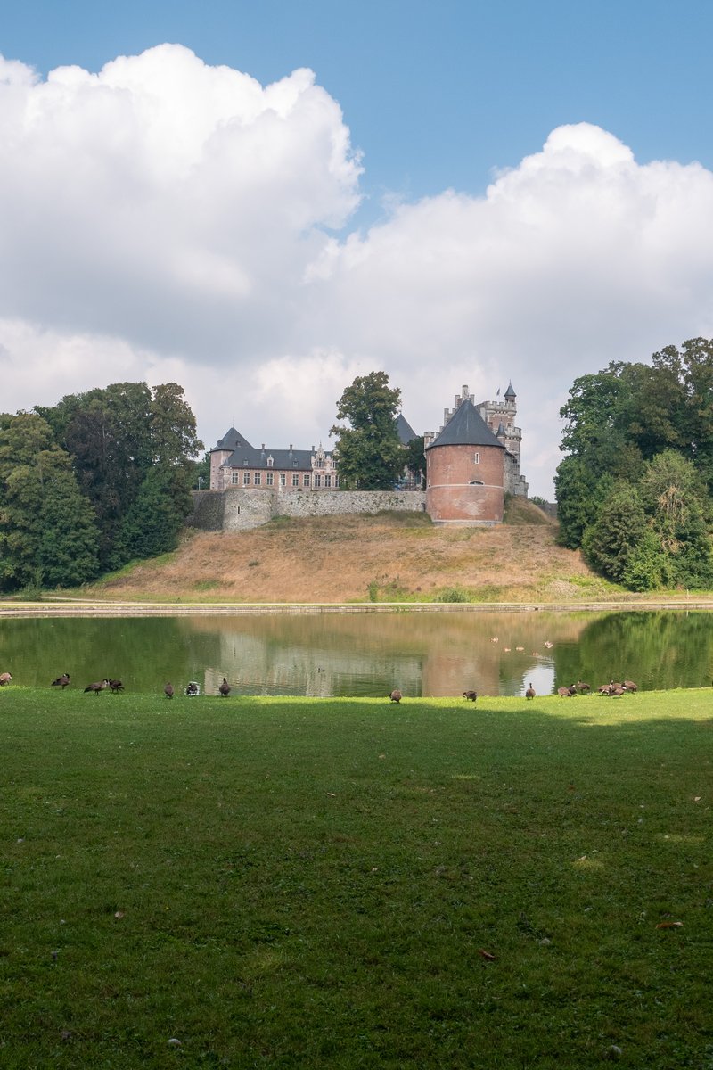 ブリュッセル近郊の公園地に映える、尖塔と蔦に覆われたガースベック城のシルエットが堀に映る景観